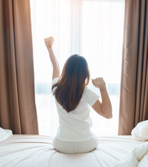 Woman sitting on bed and stretching