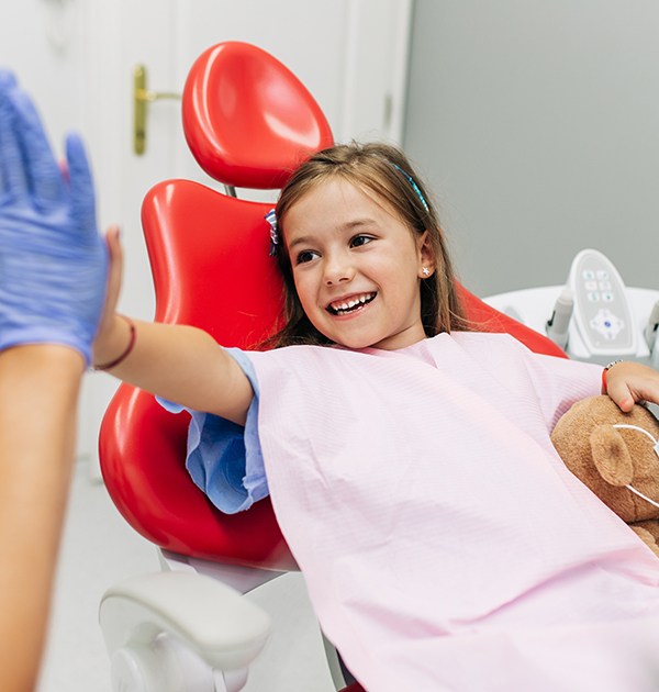 Happy young girl high-fiving her dentist