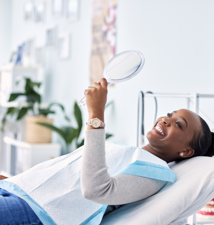 Woman admiring her smile in mirror while visiting Hillsboro dentist